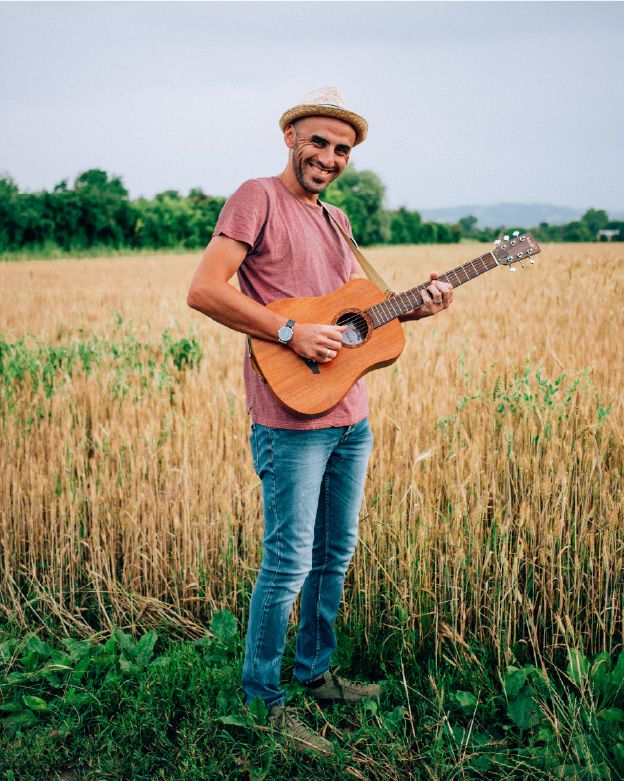 Luca con la chitarra in un campo di grano